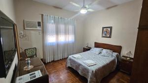 una camera con letto e finestra con ventilatore di REST HOUSE Casa familiar - garage - TV - WiFi - 2 dormitorios - Living-comedor - Cocina - Lavadero - Patio con parrilla - Alquiler temporario a Concepción del Uruguay