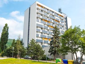 a tall white building with trees in front of it at Cosy 2 bedroom flat close to the town with parking in Bratislava