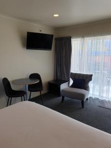 a hotel room with a bed and a chair and a table at Northcote Motor Lodge in Christchurch