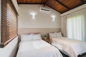 two beds sitting in a room with a window at Fazenda Pedra Lisa Hotel Boutique in Brumadinho