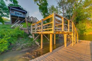 a wooden bridge over a river with a house at Rustic River Cabin with Dock and Covered Deck! in Waco