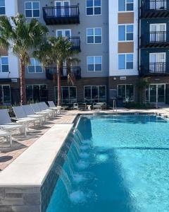 a swimming pool in front of a building with palm trees at RISE Bartram Park Condos by Barsala in Jacksonville