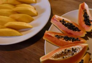 a plate of sliced papaya and a bowl of mangoes at Estalagem D'Ajuda in Arraial d'Ajuda