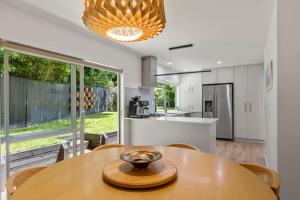 een keuken en eetkamer met een houten tafel bij Modern Sanctuary on the reserve in Auckland