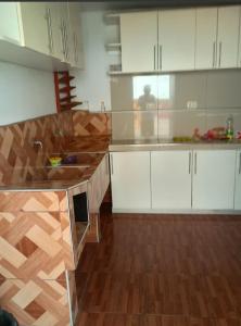uma cozinha com armários brancos e piso em madeira em Descanso de Vallecito em Hacienda Huampani