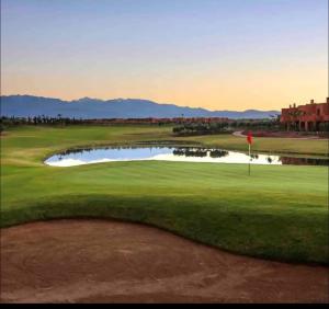 - une vue sur un parcours de golf avec un étang dans l'établissement mini-villa situee dans une residence Prestigia à Marrakech, avec une vue sur la piscine et le golf une securite 24h sur 24 et une proximite ideale de l aeroport 5 minutes C est une offre parfaite pour des vacances, à Marrakech