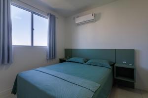 ein Schlafzimmer mit einem blauen Bett und einem Fenster in der Unterkunft Apartamento 150m da PRAIA com SACADA, WI-FI AR CONDICIONADO, PISCINA, PORTARIA 24h, PLAYGROUND e vaga de GARAGEM in Piçarras + 20 Fotos