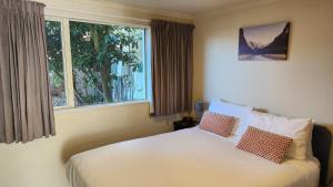 1 dormitorio con 1 cama con 2 almohadas y ventana en Northcote Motor Lodge, en Christchurch