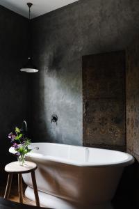 a bathroom with a white tub and a black wall at Ethelmont Rise in Sandy Bay