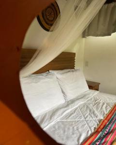 a bedroom with a bed with white sheets and a mirror at Chalés da Longa in Angra dos Reis