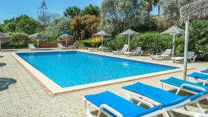 una piscina con sillas y sombrillas azules en Casas do Ramalhete, en Luz