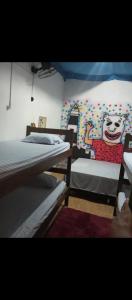 een kamer met drie bedden en een muur met een tekenfilm bij Casa do Carnaval in Olinda