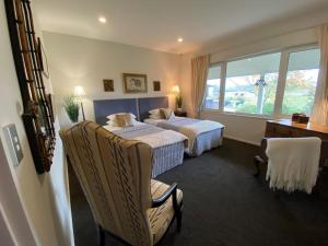 una camera d'albergo con due letti e una sedia di Chateau Pritchard a Springston