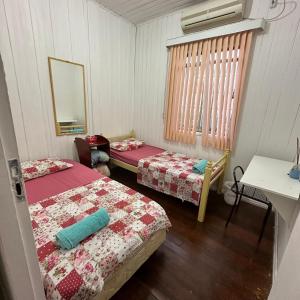 um quarto com duas camas, uma mesa e um espelho em Casa do Sussego em Foz do Iguaçu