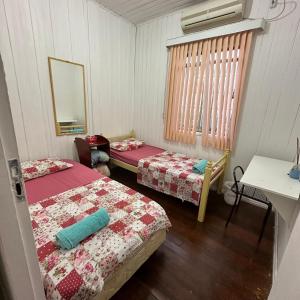 a room with two beds and a table and a mirror at Casa do Sussego in Foz do Iguaçu