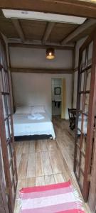 um quarto com uma cama branca e piso em madeira em Prumirim Surf Suítes em Ubatuba