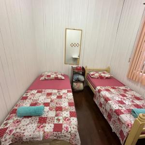 Duas camas individuais num quarto com um espelho. em Casa do Sussego em Foz do Iguaçu