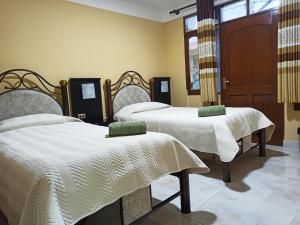 um quarto com 2 camas com edredão branco em Jurassic Hostal em Torotoro