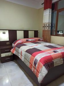 um quarto com uma cama com um edredão colorido em Jurassic Hostal em Torotoro