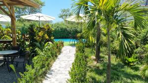 a garden with a table and a palm tree at Ballena Rey Hotel in Uvita