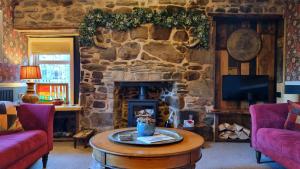a living room with a stone fireplace and a table at Luxury 3 Bedroom Cottage - Sleeps 6 in Tomintoul