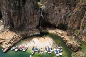 people in boats in the water at a waterfall at Suites Hidromassagem - Pousada Vale da Serra in Capitólio