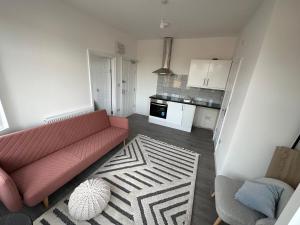 a living room with a pink couch and a kitchen at BRAND NEW!! Startlet Stays Apartments - On Elizabeth Line in London