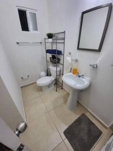 a white bathroom with a toilet and a sink at Casa Espiral in Playa del Carmen
