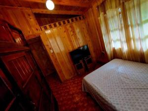 a small bedroom with a bed and a television at Cabaña Emperador – The place for QUETZALS lovers! in El Copey
