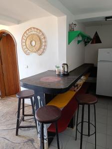a kitchen with a counter and stools in a room at Chez Arlette in Toubab Dialaw