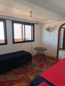 a room with a bed and a table and windows at Chez Arlette in Toubab Dialaw