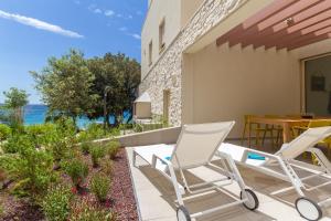 a patio with two white chairs and a table and a table and chairs at Seaside house for families with children Mandre, Pag - 22603 in Kolan
