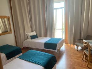 pokój hotelowy z 2 łóżkami i oknem w obiekcie Residencial Roxi w Lizbonie