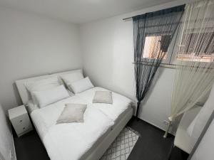 a small bedroom with a white bed and a window at Apartments with swimming pool Pag - 22607 in Pag +19 photos