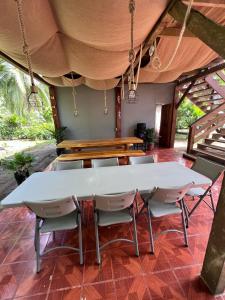 une grande table et des chaises blanches sur la terrasse dans l'établissement Shiosai Retreat Cabins, à Gandoca