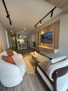 uma sala de estar com dois sofás brancos e uma televisão em Departamento Journey em Cusco