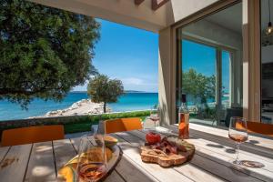 ein Tisch mit einem Teller Essen und Gläsern Wein in der Unterkunft Seaside house for families with children Mandre, Pag - 22704 in Kolan + 12 Fotos