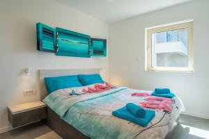 ein Schlafzimmer mit einem Bett mit blauen Kissen und einem Fenster in der Unterkunft Seaside house for families with children Mandre, Pag - 22704 in Kolan