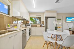 a kitchen with white cabinets and a white table and chairs at Room to rent at the Glasshouse Mountains - Wifi in Brisbane