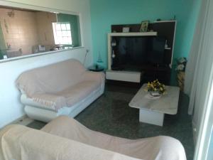 uma sala de estar com um sofá e uma televisão em Confortável, 1min da praia a pé em Niterói