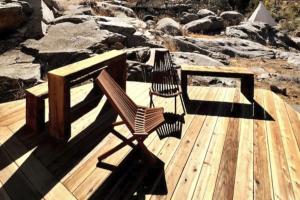 un banco de madera sentado en una terraza con rocas en Paradise Ranch Inn - Lucky Tent en Three Rivers