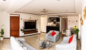 sala de estar con muebles blancos y TV en Departamento Familiar Equipado, en Cusco