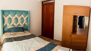a bedroom with a bed with a blue headboard at Departamento Familiar Equipado in Cusco
