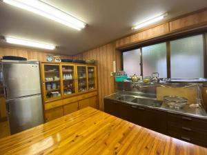 Irori 新山ふるさと体験館 في إينا: مطبخ مع ثلاجة ستانلس ستيل وطاولة خشبية