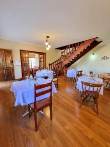 uma sala de jantar com mesas brancas e pisos em madeira em Cerejeira Guest House em Campos do Jordão