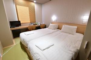 a bedroom with two beds with white sheets and a desk at Hotel A'bant Shizuoka in Shizuoka