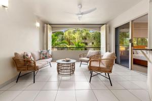 a living room with chairs and a couch and a table at Coastal Bliss - Cairns 9 Pools BBQ & Gym in Westcourt