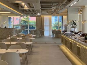 a restaurant with tables and chairs and windows at The First70 Hotel in Seogwipo