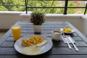 a table with a plate of food and a cup of orange juice at Hotel Balcones 70 Laureles in Medellín