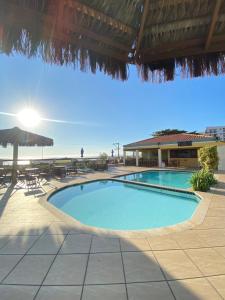 a swimming pool in a resort with tables and chairs at Varandas ao mar loft 302 Praia Grande in Arraial do Cabo